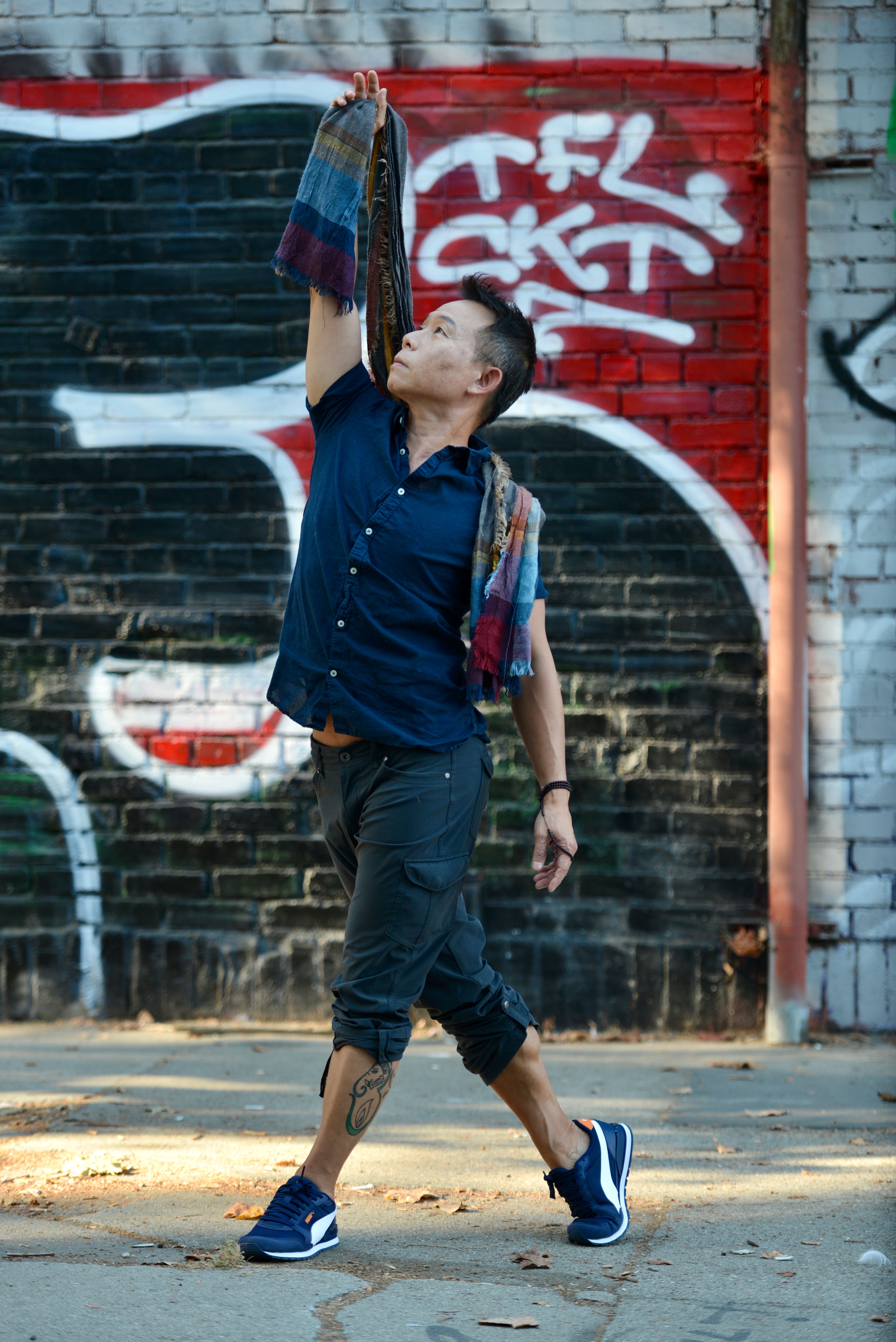 David Cho dancing in the street, arm raised with a scarf