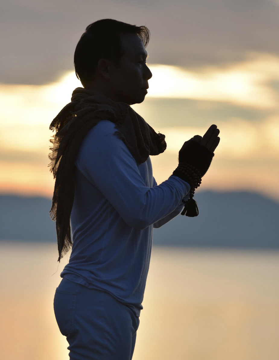 David Cho meditating in silhouette against a sunset